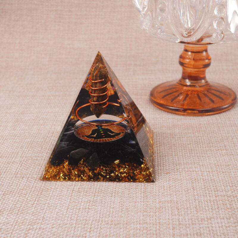 Tiger Eye and Obsidian pyramid displayed on wooden desk with crystals and meditation candles