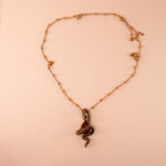 Serpent-wrapped ruby pendant against a dark velvet or neutral background