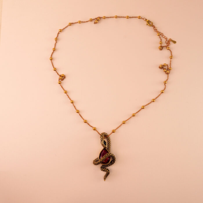 Serpent-wrapped ruby pendant against a dark velvet or neutral background