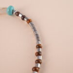 Adjustable tiger eye and turquoise gemstone bracelet with braided cord on white background