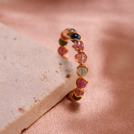Tourmaline Woven Ring showcasing calming greens, pinks, and energizing reds, with a woven band design symbolizing strength