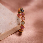 Tourmaline Woven Ring showcasing calming greens, pinks, and energizing reds, with a woven band design symbolizing strength