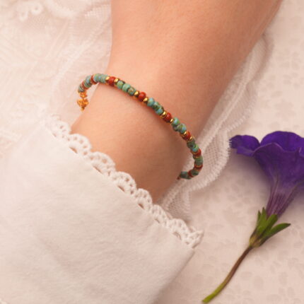 Turquoise bracelet with red agate beads shown on wrist, paired with casual outfit