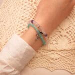 Model wearing layered gemstone bracelets in soft tones.