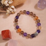 Ametrine bracelet placed in natural light on minimal textured surface.