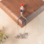 Aries zodiac necklace displayed on wooden board with amethyst, clear quartz, and red agate.