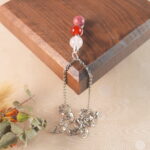 Cancer zodiac necklace displayed on wooden board with clear quartz, red agate, and rhodochrosite.