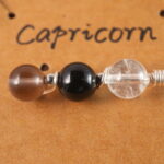 Close-up of Capricorn necklace showing clear quartz, obsidian, and smoky quartz beads.