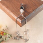 Capricorn zodiac necklace displayed on wooden board with clear quartz, obsidian, and smoky quartz.