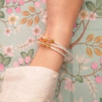 Model wearing the piece as a triple-layer bracelet around the wrist.