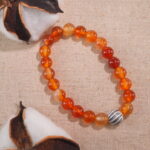 Flatlay of first flower red agate bracelet arranged on fabric.
