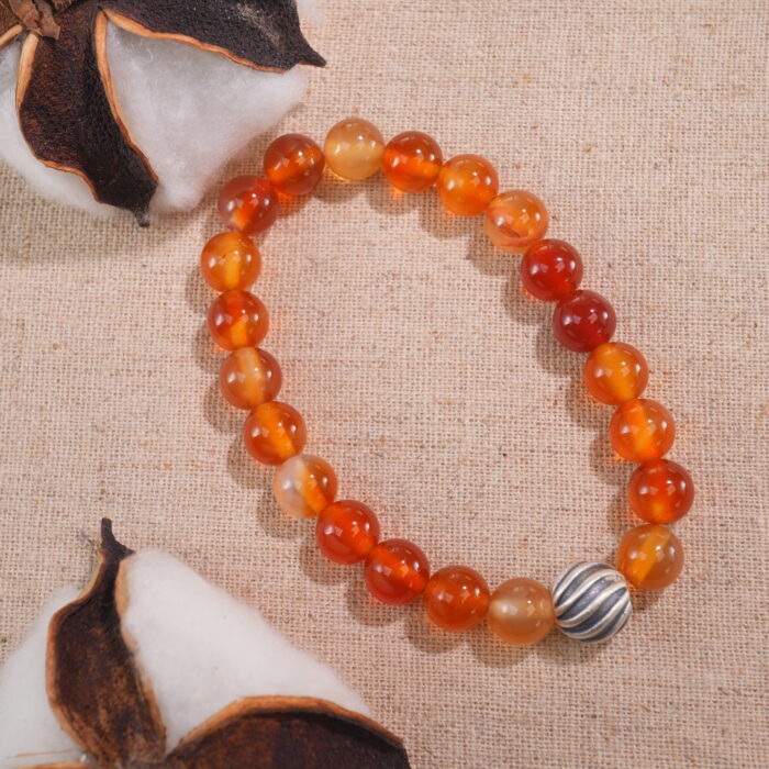 Flatlay of first flower red agate bracelet arranged on fabric.