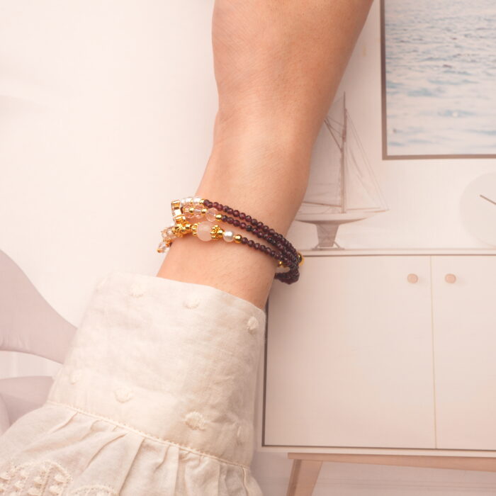 Model showcases the garnet piece worn as a bracelet, emphasizing its elegant wrap style.
