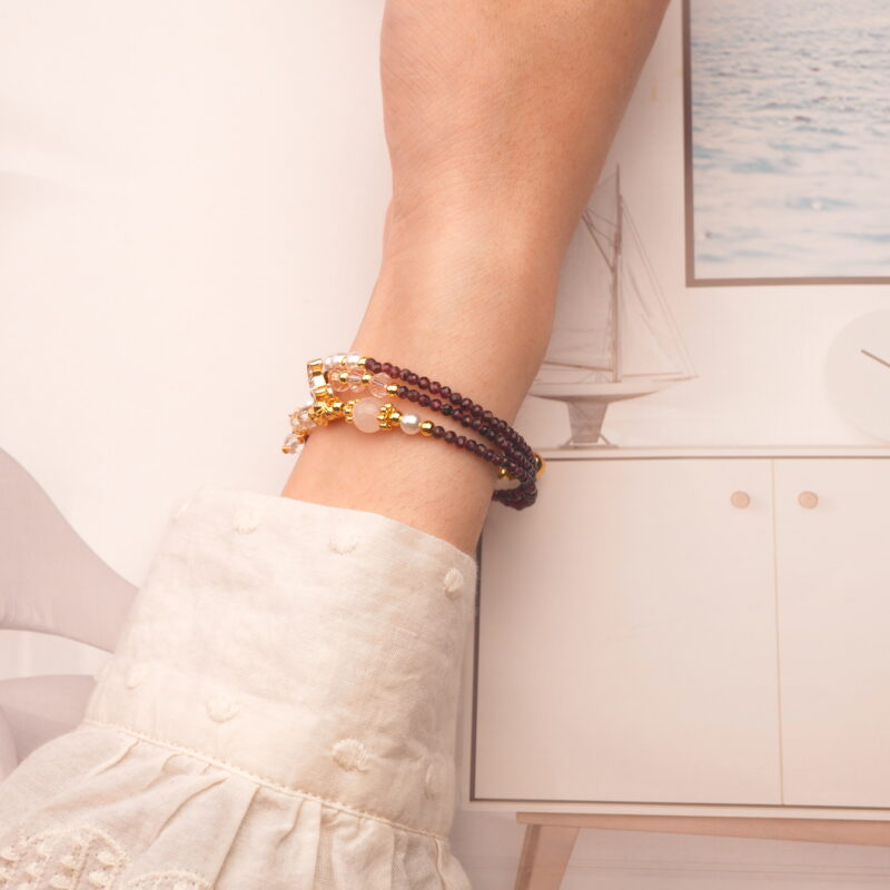 Model showcases the garnet piece worn as a bracelet, emphasizing its elegant wrap style.