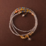 Multi-use bracelet-necklace made of gray moonstone and clear quartz, styled in a three-wrap design.