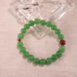 Green aventurine and red agate bracelet in natural light on a clean surface.