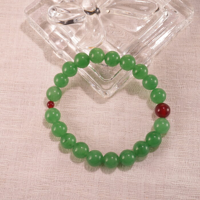 Green aventurine and red agate bracelet in natural light on a clean surface.