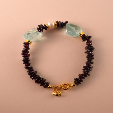 Handmade Aquarius-themed bracelet featuring garnet, pearl, and aquamarine beads laid out in a minimalist design.
