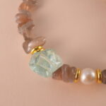 Close-up of the intricate textures in the skeleton quartz bead, beside polished pearl and aquamarine accents.