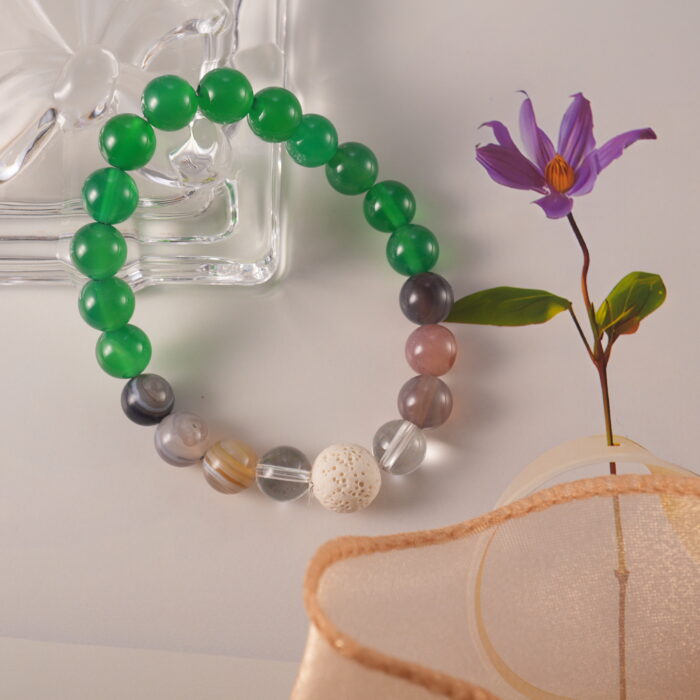 Close-up of lava stone and gemstone beaded bracelet showcasing green agate, banded agate, and clear quartz combination.