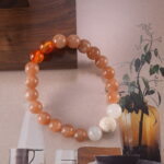 Close-up view showing carnelian, white chalcedony, and moonstone beads arranged in a harmonious color flow.