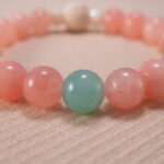 Close-up view showcasing the textured lava stone and the polished finish of rose chalcedony, strawberry quartz, and amazonite beads.