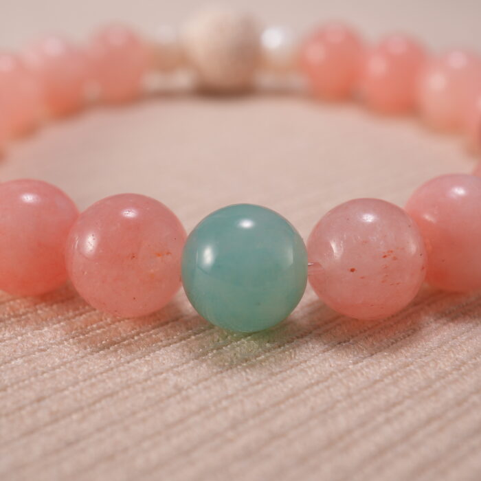 Close-up view showcasing the textured lava stone and the polished finish of rose chalcedony, strawberry quartz, and amazonite beads.