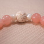 Close-up view showcasing the textured lava stone and the polished finish of rose chalcedony, strawberry quartz, and amazonite beads.