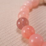 Close-up view showcasing the textured lava stone and the polished finish of rose chalcedony, strawberry quartz, and amazonite beads.