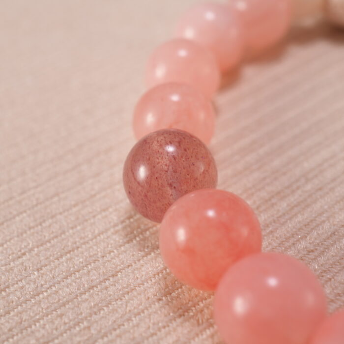 Close-up view showcasing the textured lava stone and the polished finish of rose chalcedony, strawberry quartz, and amazonite beads.