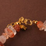Close-up of the bracelet’s Fire Quartz bead, revealing rich reddish hues and subtle internal patterns.