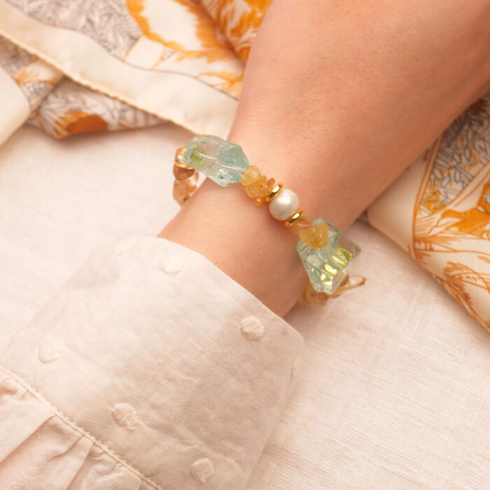 The Libra bracelet worn on the wrist, highlighting the golden threads within the rutilated quartz and the smooth luster of pearls.