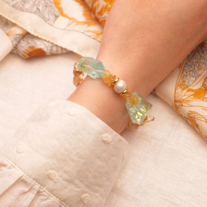 The Libra bracelet worn on the wrist, highlighting the golden threads within the rutilated quartz and the smooth luster of pearls.