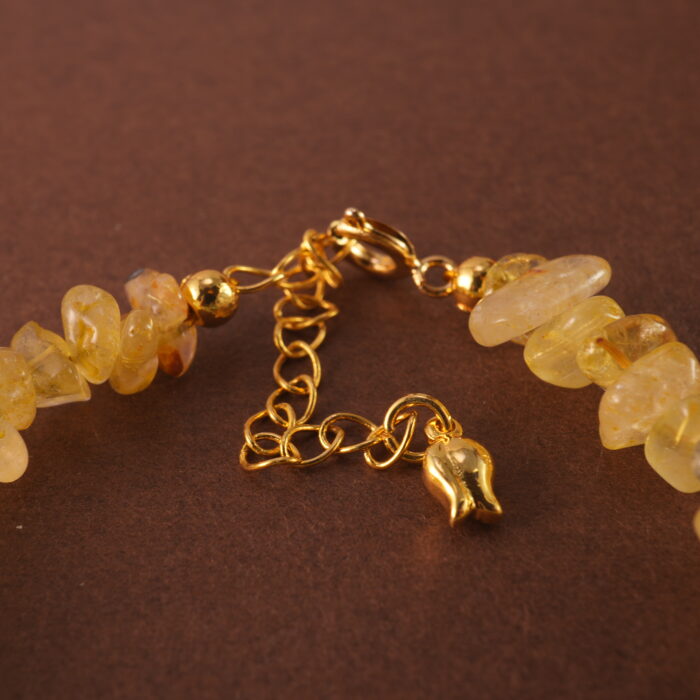 Close-up of golden rutilated quartz bead with visible golden inclusions and polished finish.