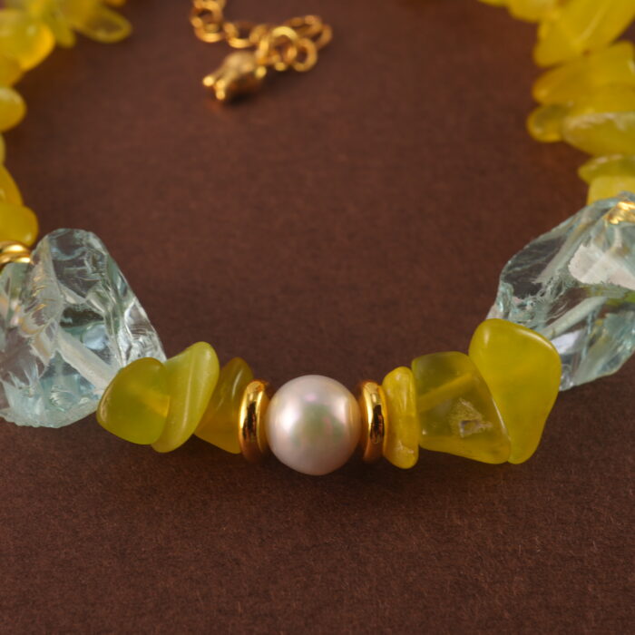 Close-up showing the natural textures and luster of peridot, aquamarine, and pearl beads.