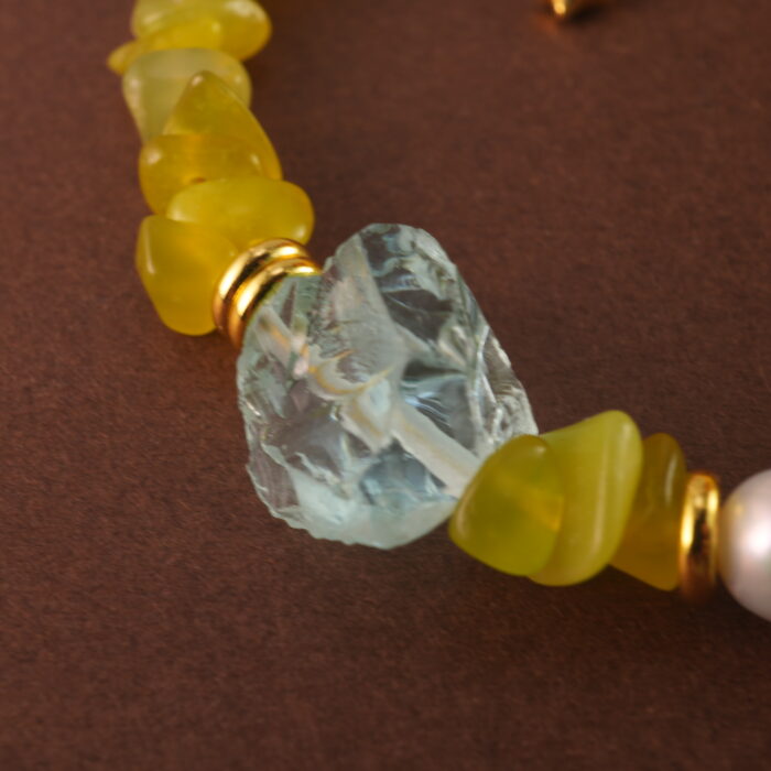 Close-up showing the natural textures and luster of peridot, aquamarine, and pearl beads.