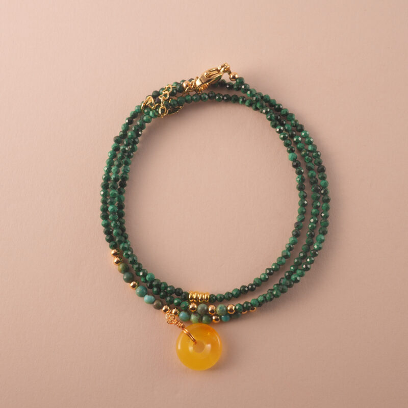 Multi-use necklace made of natural malachite beads, styled in a coiled layout to highlight its vibrant green tones.