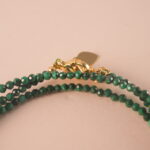 Close-up of malachite beads showing their natural banding patterns and smooth polished surface.
