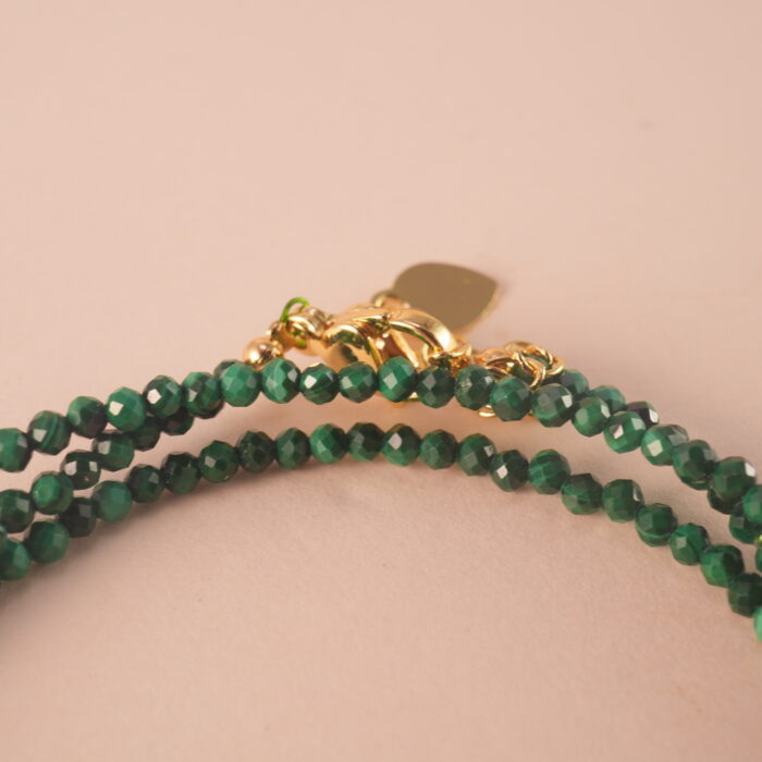 Close-up of malachite beads showing their natural banding patterns and smooth polished surface.