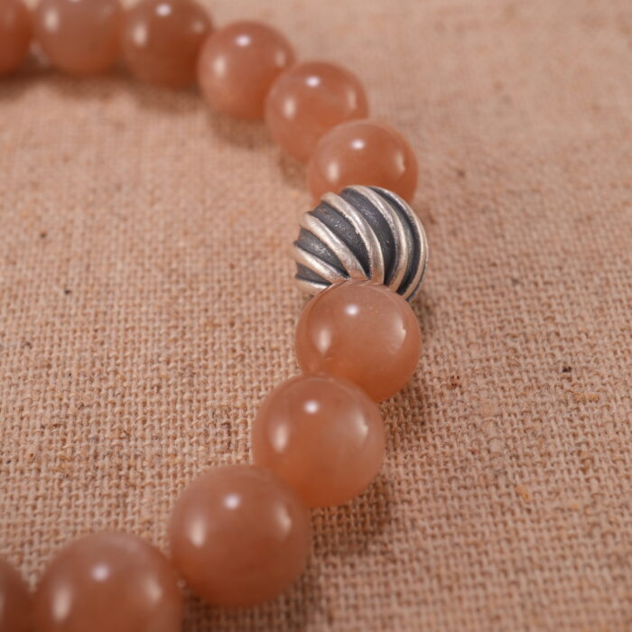 Close-up of peach moonstone bracelet with S925 silver detailing.