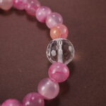 Close-up of pink chalcedony and clear quartz bracelet with smooth beads.