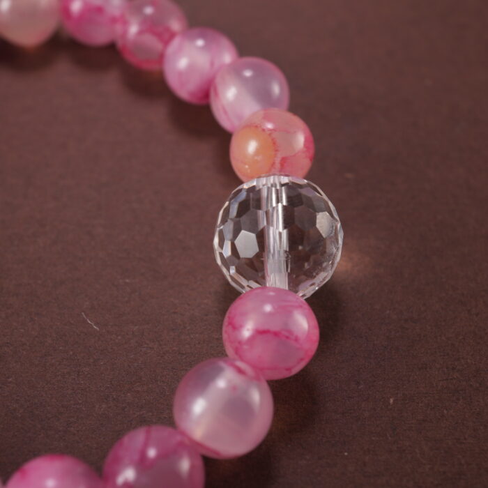 Close-up of pink chalcedony and clear quartz bracelet with smooth beads.
