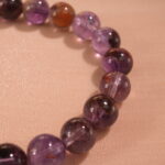 Close-up of purple phantom quartz bracelet with layered crystal inclusions.