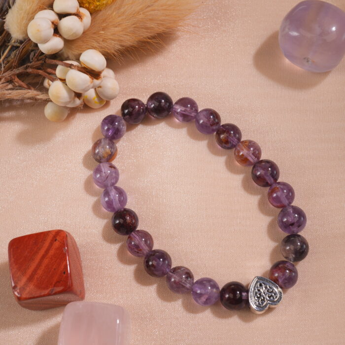 Purple phantom quartz bracelet in natural light on textured background.