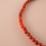 Close-up of red agate bracelet with smooth beads and deep red color.