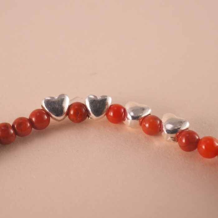 Close-up of red agate bracelet with smooth beads and deep red color.