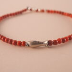 Close-up of red agate bracelet with smooth beads and deep red color.