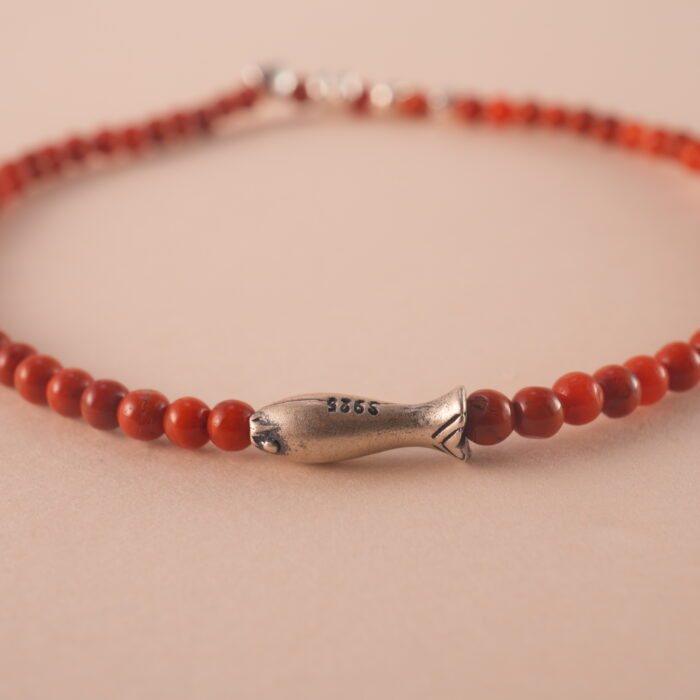 Close-up of red agate bracelet with smooth beads and deep red color.