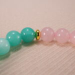 Close-up of rose quartz and amazonite bracelet in soft pastel colors.