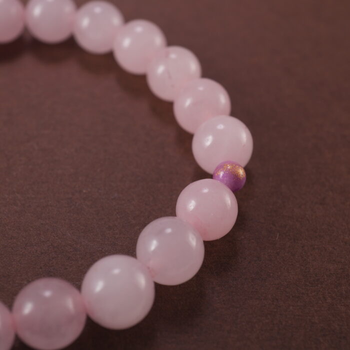 Close-up of rose quartz bracelet with soft pink translucent beads.